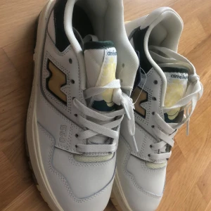 New Balance 550 Aimé Leon Dore sneakers - Säljer ett par New Balance 550 Aimé Leon Dore sneakers i vitt med beige och mörkgröna detaljer. Skorna har snörning, Ortholite innersula och cool retro-vibe. Tillverkade i skinn och syntet, med tydlig 550-logga på sidan och klassisk N-logga i beige mocka. Tyvärr jag slängde lådan lådan så jag HAR INTE själva lådan till skorna.