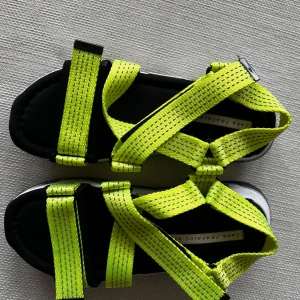 Neongula sandaler från Zara Trafaluc - Chunky sandaler från Zara Trafaluc med neongula remmar och svart/vit sula. Remmarna är justerbara och i syntetmaterial, sulan är kraftig och har coola svarta detaljer på sidorna. Perfekta för att sticka ut i sommarens alla looks.