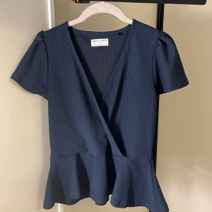 Mörkblå omlottopp - Supersnygg mörkblå omlottopp från Holly & White (Lindex) med v-ringning, korta puffärmar och volangkant nedtill. Knappt använd.❣️❣️