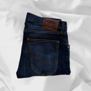 Lee Jeans - Coola jeans från Lee, modell Luke. W31 L32 – enkla att matcha och sköna att bära. Ett stilrent val, noggrant utvalt med omsorg av AM Clothing.  📩 Frågor? Hör gärna av dig! 📲 Följ oss här på Plick för fler uppdateringar. ♻️ Tack för att du handlar mer hållbart med AM Clothing!