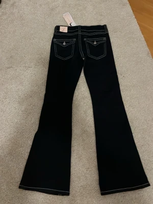 Nya Gina Tricot Mörkblå chunky flare tall jeans  - Tall flare jeans med utsvänga ben. Snygga mörkblå jeans med vita kontrastsömmar och fickor med lock och knapp bak. Säljs nya då jag fick dem i julklapp och de var för stora. ❤️