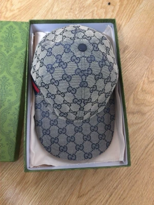 Gucci keps med GG-mönster - Snygg keps från Gucci i beige och blått med klassiskt GG-monogram över hela kepsen. Kepsen har böjd skärm och justerbar passform. Materialet är canvas med insida i mörkblått tyg. Perfekt för dig som vill ha en exklusiv accessoar.