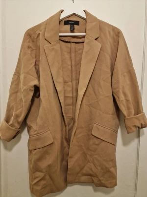 Forever 21 beige kavaj  - Kavajen har  en loose passform som ger en avslappnad men ändå snygg look. Snygg att slänga över en t-shirt eller skjorta. Endast tvättad vid flytt.