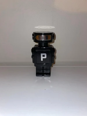 Paco Rabanne Black XS parfymflaska - Unik parfymflaska från Paco Rabanne formad som en svart robot med silverdetaljer och ett stort P på bröstet. Flaskan har en futuristisk design och är tillverkad i plast och metall. Perfekt för dig som gillar coola och annorlunda parfymflaskor.