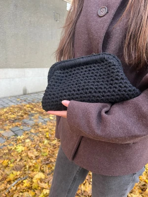 Handvirkad Clutchväska i svart - Vi är ett UF-företag som säljer handvirkade Clutchväskor! 🩷 Denna väska är i färgen svart. Väskan har en unik form och känns både trendig och handgjord. Perfekt för dig som gillar en personlig touch på din outfit.OBS‼️ KÖPAREN STÅR FÖR FRAKTEN 