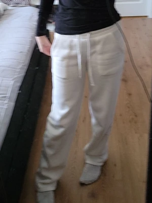 Vita mjukisbyxor med snörning - Säljer ett par vita mjukisbyxor med snörning i midjan och raka ben. Byxorna har två sidofickor och är tillverkade i mjukt bomullsmaterial. Perfekta för chill dagar eller när du vill ha det extra bekvämt.