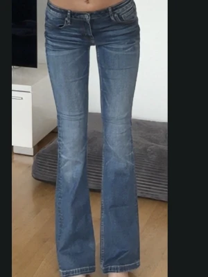 Vintage bootcut jeans blå - Snygga blå vintage  jeans med bootcut passform och klassiska fem fickor. Jeansen har låg midja och är tillverkade i slitstarkt bomullsdenim. Perfekta för dig som gillar en avslappnad men ändå trendig look.