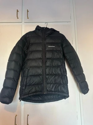 Svart dunjacka från Peak Performance - Snygg svart dunjacka från Peak Performance med huva och dragkedja framtill. Storlek M. Fint skick dock lite sminkfläckar på insidan längst upp vid dragkedjan (se bild), annars inget annat! Kan skickas! Skriv om ni vill ha mer information 😇