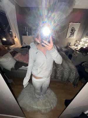 Ljusgrå zip-hoodie från Puma - Ljusgrå hoodie med dragkedja från Puma. Tröjan har huva, långa ärmar och två fickor framtill. Klassisk Puma-logga på bröstet. 