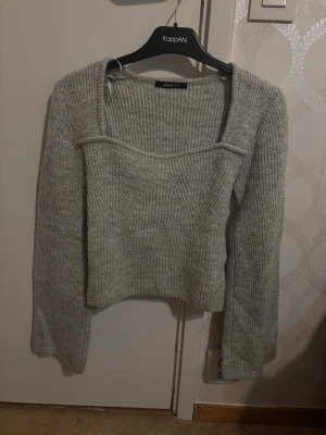 Grå ribbstickad tröja Gina Tricot - Säljer en ljusgrå ribbstickad tröja från Gina Tricot med fyrkantig ringning och långa ärmar. Tröjan har en croppad passform och är gjord i mjukt stickat material. Perfekt för lager på lager och enkel att styla till olika outfits.