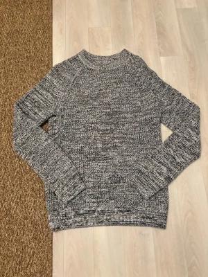 Gråmelerad stickad tröja East West - Snygg gråmelerad stickad tröja från East West med rund halsringning och långa ärmar. Tröjan har aldrig använts 