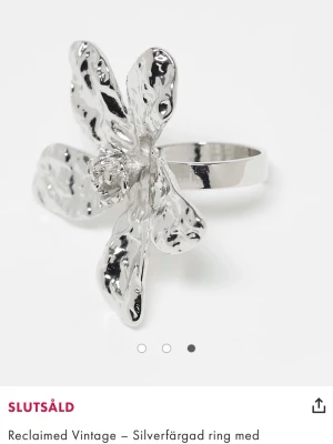 Ring med blomma - reclaimed vintage - NY - Statementring i silverfärg från Reclaimed Vintage med en stor, abstrakt blomformad dekoration. Ringen har en glansig finish och en bred ringbas som ger en cool och unik look. Helt ny, men har mest guldsmycken så den kommer inte till användning. Storlek XS, skulle kunna gissa på ca 15mm 