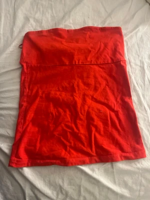 Röd tubtopp från Gina Tricot - En enkel och snygg röd tubtopp från Gina Tricot. Toppen är axelbandslös och har en rak passform, perfekt att styla till olika looks. Tillverkad i mjuk bomull som känns skön mot huden.