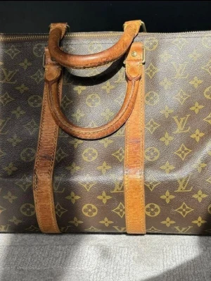 Louis Vuitton keepall 45 - Vintage LV. Kan användas som weekendbag, handbagage eller gymbag.  Mått ca 45 x 25 x 20 cm.  Bra skick för att vara vintage men har lite  bruksslitage och vissa torra skinndetaljer, dragkedjan går att stänga och öppna men kan endast att dras åt ett håll. De små flärparna på sidorna gått av.   Inköpt på Bukowskis, kvitto finns.