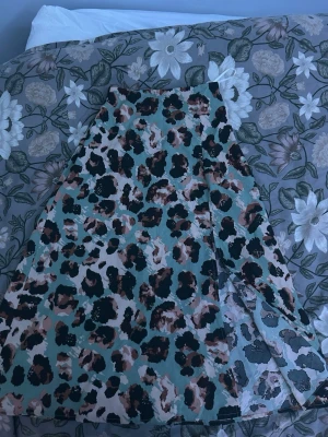 Leopardmönstrad kjol från SHEIN - Trendig leopardmönstrad kjol från SHEIN i A-linjeformad modell. Kjolen har en mix av beige, svart, brun och grön färg och är tillverkad i ett lätt syntetmaterial. Perfekt för dig som vill sticka ut med ett djurmönster.