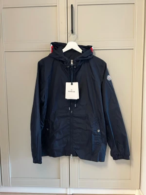 Marin blå windbreaker - Marinblå windbreaker väldigt snygg mer rött och vitt linjer på luvan