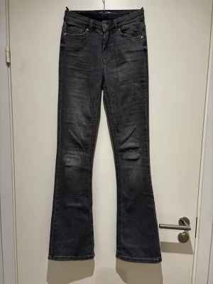 Grå bootcut jeans från ONLY - Snygga grå bootcut jeans från ONLY med klassisk femficksmodell och knappgylf. Jeansen har en lätt utsvängd passform nedtill och är tillverkade i mjukt denimtyg. Knappt använda 
