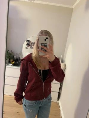 Vinröd hoodie med dragkedja - Vinröd hoodie från Lager 157 med dragkedja framtill och två fickor. Klassisk modell med huva och ribbade muddar vid ärmslut och nederkant. Perfekt för en avslappnad och stilren look. Knappt använd, möjligtvis någon enstaka gång💗