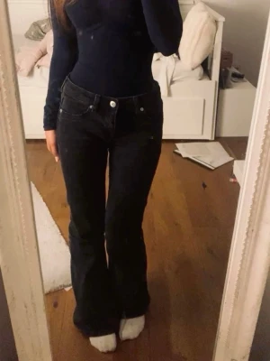 Svarta bootcut jeans  - Snygga svarta jeans med klassisk bootcut-modell. Jeansen har fem fickor, hällor för bälte och är tillverkade i ett robust jeanstyg. Perfekta för dig som gillar en tidlös och stilren look.