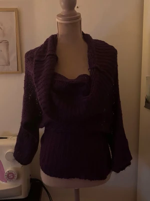 Lila stickad tröja Offshoulder - Säljer en lila stickad offshoulder tröja med krage som kan stylas på olika sätt. Tröjan har lång ärm och ribbstickade detaljer vid midja. Postar på mindre än 24h.