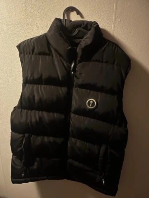 Svart dunväst från Trapstar - Säljer en svart dunväst från Trapstar. Köpte den för cirka 2000kr, köptes i 2024 oktober anvönde den fram till slutet av november. Säljer den för den har blivit lite för stor, den är storlek L. Inget fel med vesten finns en inne ficka. Finns QR kod för att scanna. Priset kan sänkas vid snabb affär. Tar endast kontant pgr Swish funkar ej