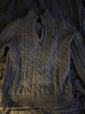 stickad tröja Polo Ralph Lauren - Snygg grå kabelstickad tröja från Polo Ralph Lauren med halv dragkedja och hög krage. Storlek M