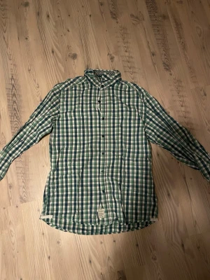 Grönvitrutig skjorta från Esprit - Snygg långärmad skjorta från Esprit i grönt och vitt rutigt mönster. Skjortan har klassisk krage, knäppning framtill och är tillverkad i mjuk bomull. Perfekt för en avslappnad men stilren look. Står inte storlek men skulle säga M. PRISET GÅR ATT DISKUTERA 