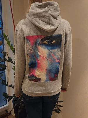 Grå hoodie från ”the cool elephant” - En stilren grå hoodie med huva och dragsnören. Hoodien har en klassisk magficka och ribbade muddar vid ärmslut och nederkant. Perfekt för en avslappnad look och enkel att matcha med jeans eller joggers.