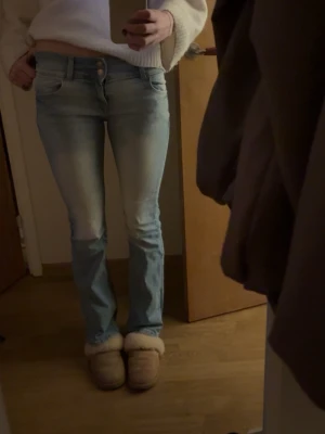 Ljusblå bootcut jeans - Säljer ett par ljusblå bootcut jeans med snygga tvättade detaljer. Jeansen har klassisk femficksmodell och normal passform. Perfekta för en avslappnad och trendig look.