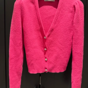 Rosa kofta från Zara med pärlknappar - Superfin rosa kofta från Zara med fluffig stickad känsla och glittrande pärlknappar i blomform. Koftan har v-ringning, lång ärm och croppad passform. 