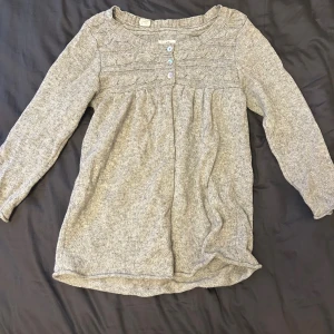 Grå stickad kofta från L.O.G.G. H&M - Mysig grå stickad kofta från L.O.G.G. H&M med dekorativa stickade detaljer upptill och tre knappar framtill. Koftan har tre kvarts ärm och en avslappnad passform, perfekt för lager-på-lager under kyliga dagar.