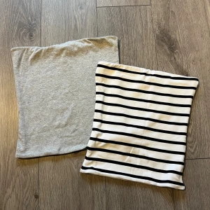 Crop top  - Säljer två tubtoppar från Bik Bok, en i ljusgrått och en vit med svarta ränder. Båda är bandeau-modell och ärmlösa, perfekta för sommaren. Tillverkade i mjuk bomull med stretch för skön passform. Den randiga toppen har klassiskt svartvitt mönster, den andra är enkel och grå.