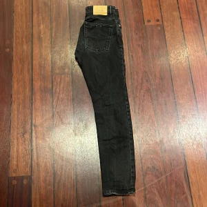 Svarta jeans  från Pull&Bear - Svarta jeans från Pull&Bear i regular fit med klassisk femficksdesign och knappstängning. Jeansen har en mörk tvätt och raka sömmar, tillverkade i jeansmaterial med snyggt Pull&Bear-läderpatch bak i midjan. Perfekt för dig som gillar en stilren look.