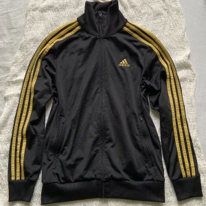 Adidasjacka!💋 - En svart och gul Adidasjacka i bra skick! Den har varit väl använd men väl omhändertagen. Storleken är egentligen för barn, 164 EU men den passar mig. Den är visserligen liten men på ett snyggt sätt. Skitsnygg verkligen och den som kommer bära den likaså!💋