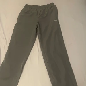 Gröna träningsbyxor från Reebok S - Snygga gröna träningsbyxor från Reebok i storlek S. Byxorna har elastisk midja och är tillverkade i ett lätt syntetmaterial med meshfoder. Perfekta för gymmet eller chill hemma. Diskret Reebok-logga broderad på benet.