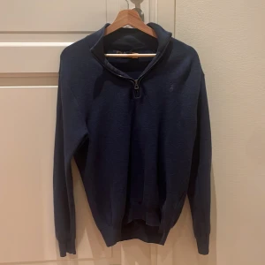 Marinblå half zip tröja Polo Ralph Lauren - Snygg marinblå långärmad tröja från Polo Ralph Lauren med half zip och hög krage. Tröjan har en klassisk, normal passform och är tillverkad i mjuk bomull. Perfekt för dig som gillar stilrena och tidlösa plagg med diskret broderad logga på bröstet.