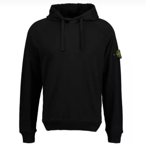 Svart hoodie från Stone Island - Svart hoodie från Stone Island med klassisk logotyp-patch på vänster ärm. Tröjan har huva med snörning, ribbade muddar och lång ärm. Tillverkad i mjuk bomull för skön komfort. Perfekt för dig som gillar streetwear och vill ha en clean look.