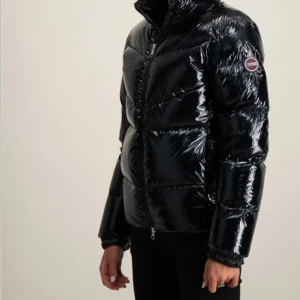 Svart glansig dunjacka från Colmar - Snygg svart dunjacka från Colmar i nyskick endast använd enstaka gånger. Jackan har hög krage, dragkedja framtill och Colmar-logga på ärmen. 