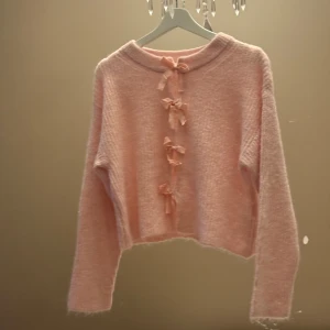 Rosa barnkofta med rosetter från Gina Tricot - 🎀 Supergullig ljusrosa stickad kofta från Gina Tricot i storlek 146/152, med söta rosetter framtill. Perfekt för dig som gillar mjuka och fluffiga plagg med extra detaljer. Oanvänd 🎀