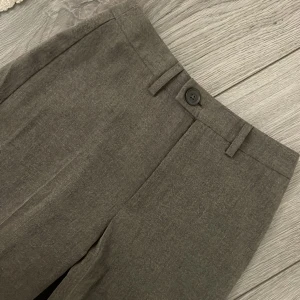 Mörkgrå kostymbyxor från Stradivarius - Mörkgråa kostymbyxor från Stradivarius med raka ben och klassisk passform. Byxorna har hällor för bälte, knapp och dragkedja framtill. Perfekta för en clean och stilren look.