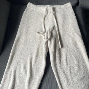 Vita mjukisbyxor med snörning + matchade linne - Supermysiga vita mjukisbyxor i frottéliknande material med dragsko i midjan. Perfekta för chill dagar hemma och har en loose fit för extra komfort. Matcha gärna med en crop top för en avslappnad look. byxorna är i storlek L och linnet storlek M 