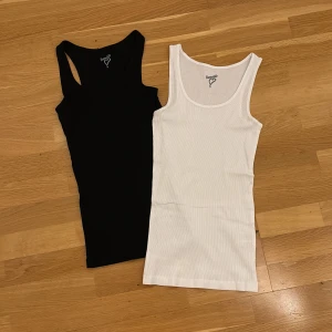 Svart och vit ribbad linnetopp - Två  linnetoppar från Favourite st S i båda i svart och vitt. Båda är ribbade,  klassisk ärmlös design med rundad halsringning. 