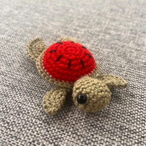 virkadvattenmelons sköldpadda - Bilderna visar en handgjord, virkad sköldpadda med vattenmelonskal. Produkten är liten och söt, perfekt som dekoration eller leksak. 