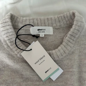 Beige stickad tröja från Gina Tricot - Supermysig helt ny beige stickad tröja från Gina Tricot i ullblandning. Tröjan har rund hals, ribbade muddar och lång ärm med loose passform. Perfekt för kyliga dagar och enkel att styla med jeans eller kjol. Snygg och enkel design som funkar till allt. Orginalpris 400