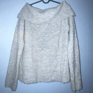Grå stickad axel tröja Gina Tricot - Mysig grå stickad axel tröja från Gina Tricot med bred krage och långärmad design. Tröjan har en loose passform och ribbade detaljer vid krage och nederkant. Perfekt för kyliga dagar och enkel att matcha med jeans eller kjol. Passar bra nu till vintern!