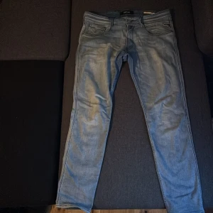 Replay Anbass ljusblå jeans herr - Säljer ett par Replay Anbass jeans i ljusblå tvätt. Klassisk femficksmodell med dragkedja, raka ben och broderade bakfickor. Jeansen är i bomull och har en modern, slim passform. Perfekta för dig som gillar stilrena och bekväma jeans. Längd 32. Har knappt använt dom.