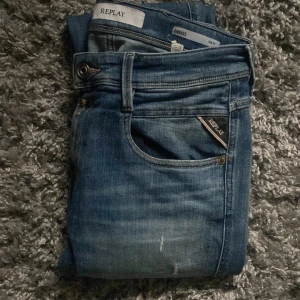 Replay Anbass slim fit jeans blå - Säljer ett par blå Replay Anbass jeans i slim fit med klassisk femficksdesign och snygga slitningar. Jeansen har normal midja, raka ben och detaljer som Replay-logga på fickan. Perfekta för dig som gillar en smalare passform och stilren look.  Storlek 29/32Kom gärna med frågor vid funderingar!!