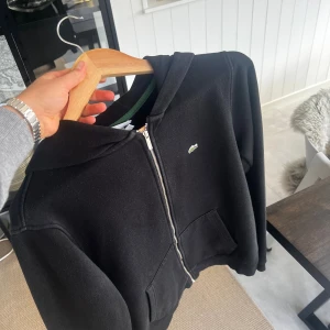Lacoste Zip Hoodie, 176, Svart, Mycket Bra Skick - Hej! Säljer nu den här Lacoste zip hoodien då den inte kommit till användning. Tröjan är gjord av bomull, använd ett fåtal gånger och i mycket bra skick. Perfekt lagerplagg inför vintern.  Storlek: 176 (14-16 år) Färg: Svart  Kan skickas (köparen står för frakt) eller hämtas i Täby. Först till kvarn gäller.  Vid frågor eller för fler bilder - skicka gärna ett meddelande.  Mvh William