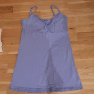 Ljusblå blus från Mexx - Söt ljusblå lång blus från Mexx med smala axelband och v-ringning. Blusen har broderad spetskant nertill som ger en extra detalj. Perfekt för varma dagar och enkel att styla med sneakers eller sandaler.