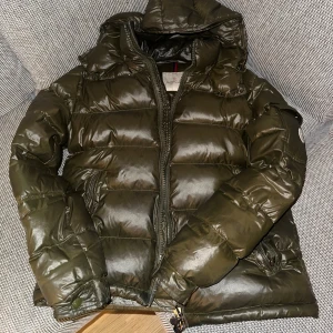 Moncler maya jacka (storlek 1/S) - Skicks bedöms enligt bilder, enligt mig 8/10. Har sparsamt använts i drygt över 1 år. Säljer endast jackan utan tags eller liknande. Har fler bilder via pm. Jackan är army green, NFC scan finns tillgänglig på denna moddelen.